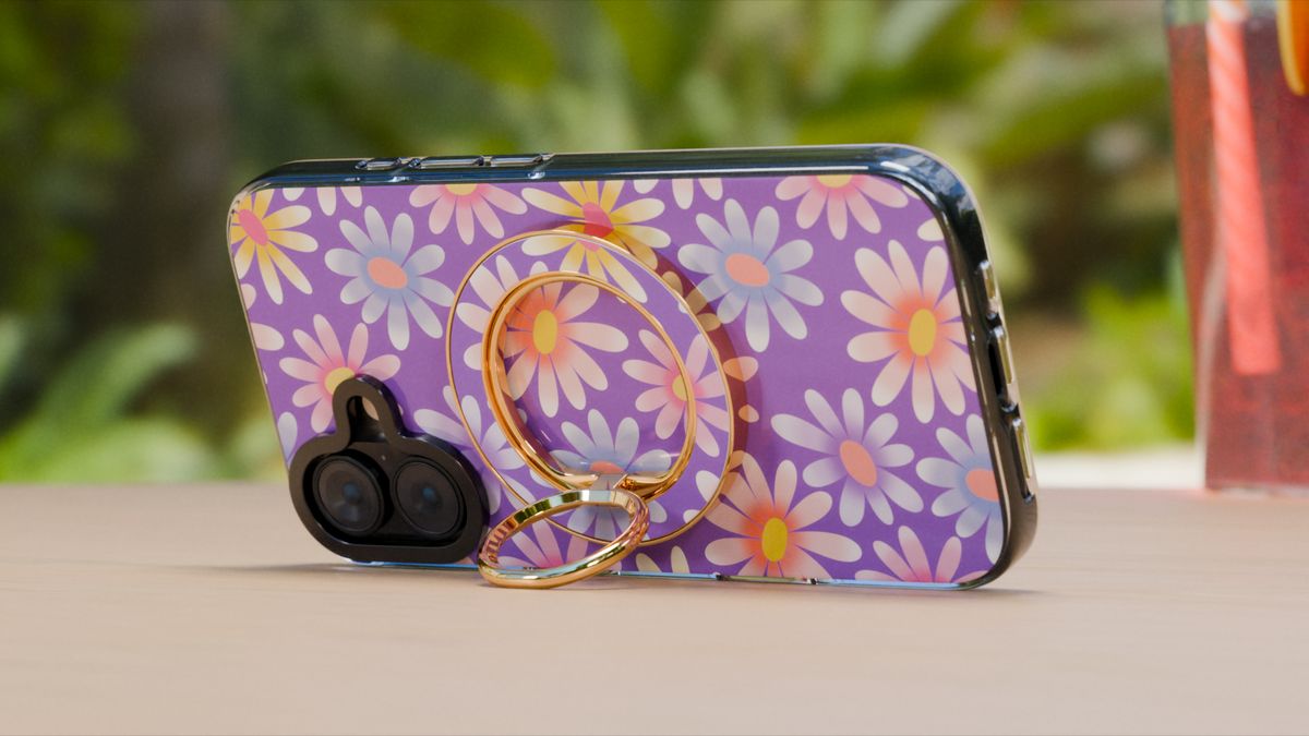 A phone with a printed case standing on its gold MagSafe ring holder